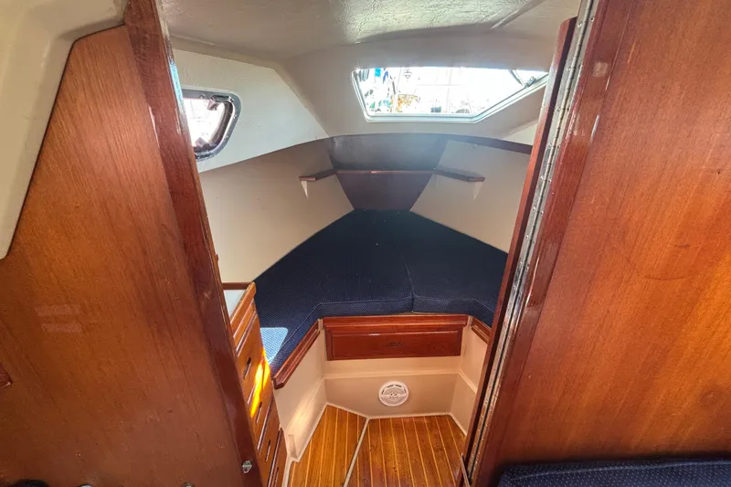Interior cabin of a 1988 Catalina 34 sailboat with wood finish and cozy sleeping area.