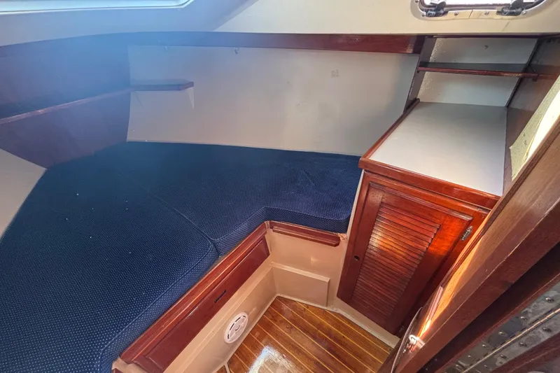 1988 Catalina 34 yacht interior with blue cushioned berth and wooden cabinetry.