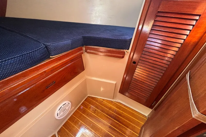 Interior cabin of 1988 Catalina 34 sailboat with wooden finish and blue cushions.