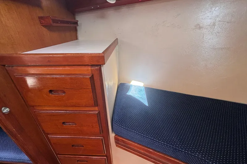 Interior of 1988 Catalina 34 sailboat with wooden drawers and blue cushioned seating.
