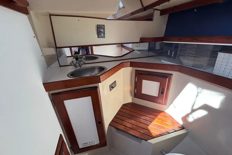Interior of 1988 Catalina 34 sailboat with compact kitchen and wooden accents.