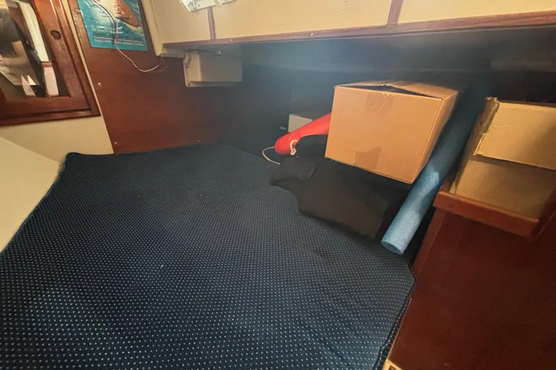 Interior cabin of 1988 Catalina 34 sailboat with storage boxes and blue mat.