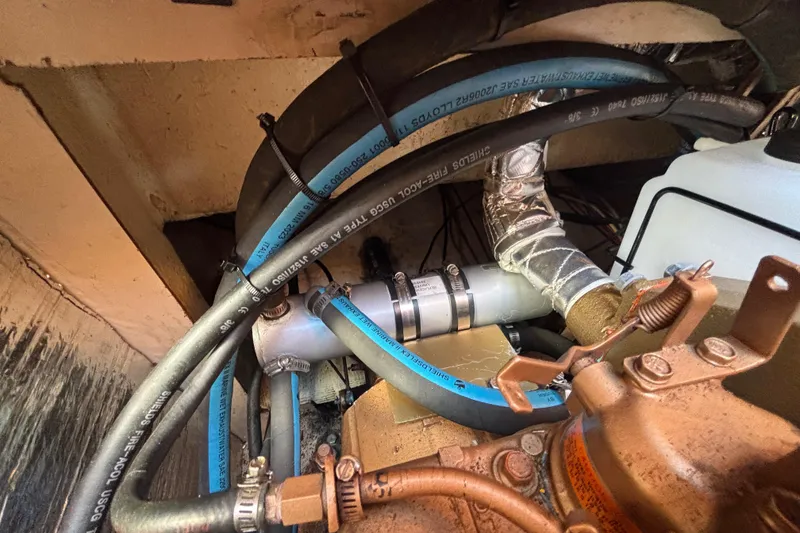 Engine compartment of a 1988 Catalina 34 sailboat with hoses and fittings.