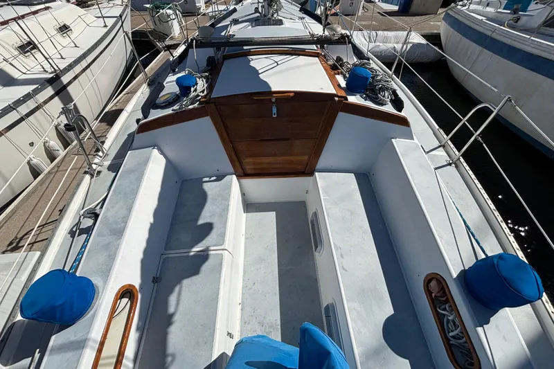 1988 Catalina 34 sailboat cockpit with wooden hatch and blue cushions at marina.