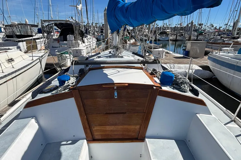 1988 Catalina 34 sailboat docked at marina, featuring wooden hatch and blue sail cover.