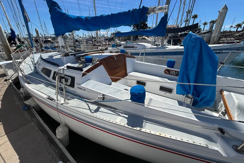 1988 Catalina 34 sailboat docked at marina, featuring blue sail covers and clean deck.