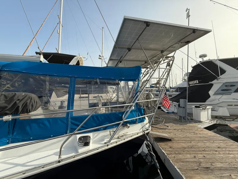 Beneteau Idylle 15.50 sailboat, 1986 model, docked with solar panels and blue canopy.