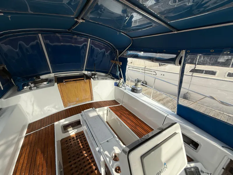 1986 Beneteau Idylle 15.50 yacht cockpit with wooden flooring and blue canopy.