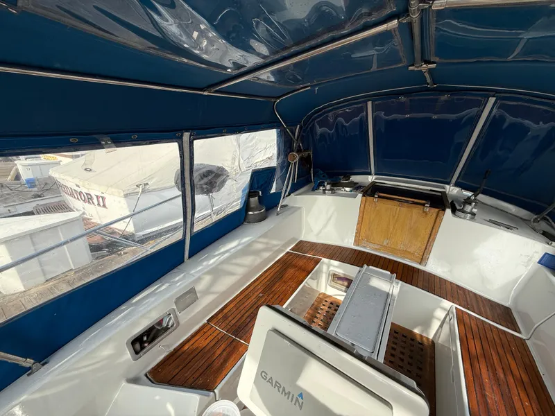 1986 Beneteau Idylle 15.50 cockpit with blue canopy and wooden flooring.