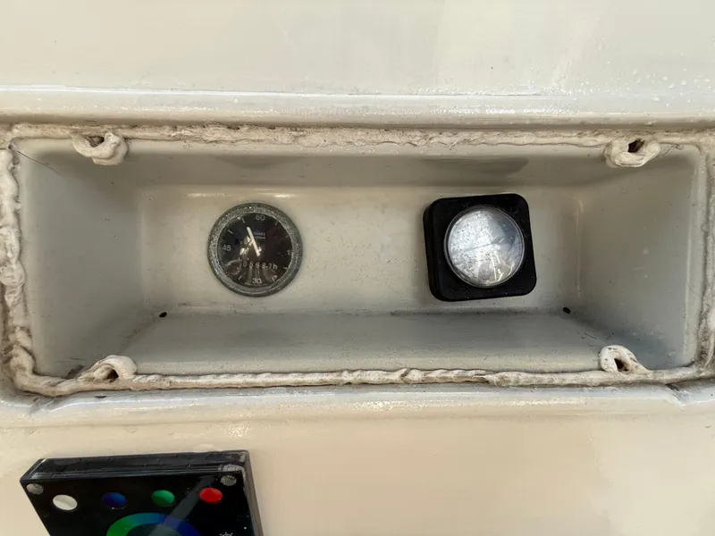 Control panel of a 1986 Beneteau Idylle 15.50 sailboat, featuring a gauge and button.