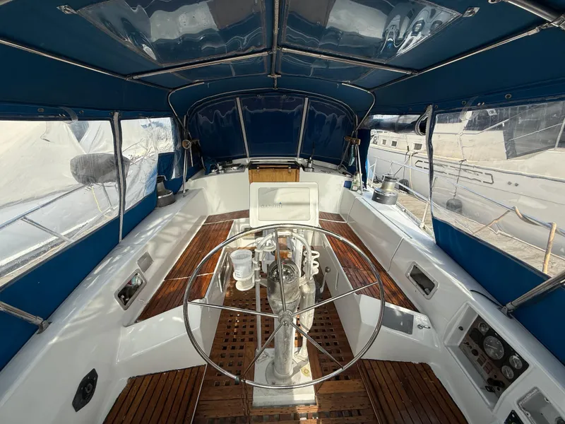 1986 Beneteau Idylle 15.50 yacht cockpit with wooden flooring and blue canopy.