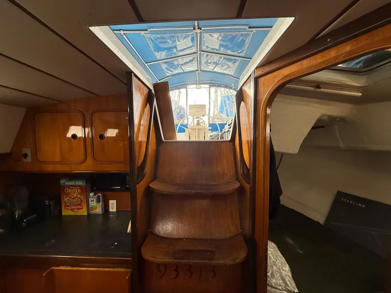 Interior view of 1986 Beneteau Idylle 15.50 sailboat, featuring wooden stairs and cabinetry.
