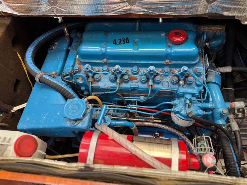 Blue engine of a 1986 Beneteau Idylle 15.50 sailboat, featuring a red fire extinguisher.