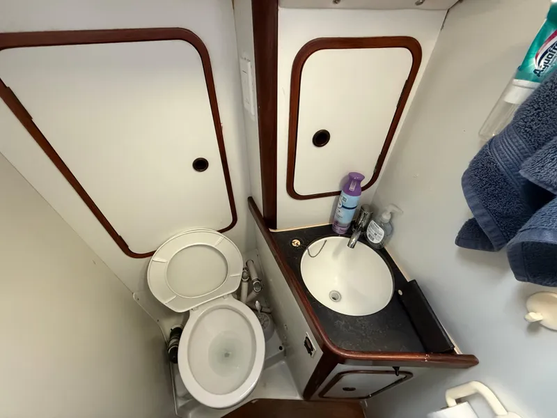 Compact bathroom in a 1986 Beneteau Idylle 15.50 sailboat, featuring a toilet and sink.