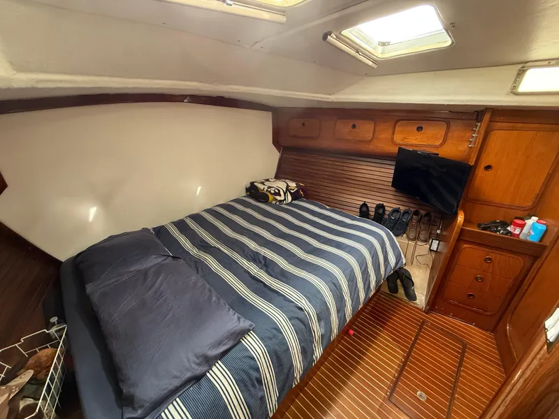 Cozy cabin interior of 1986 Beneteau Idylle 15.50 with striped bedding and wooden accents.