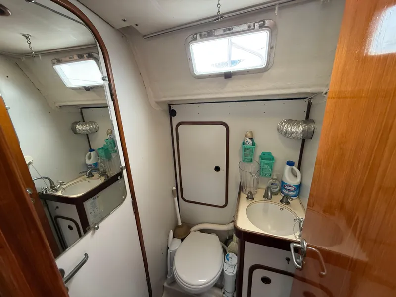 Bathroom interior of 1986 Beneteau Idylle 15.50 sailboat, featuring sink and toilet.