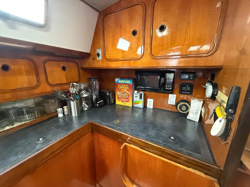 1986 Beneteau Idylle 15.50 yacht kitchen with wooden cabinets and modern appliances.