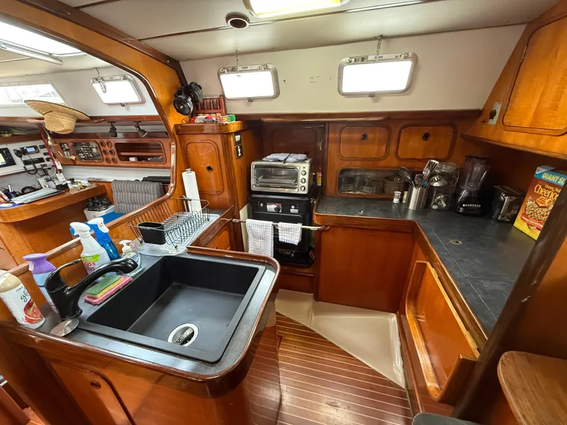 Interior of 1986 Beneteau Idylle 15.50 yacht kitchen with wooden cabinetry and appliances.