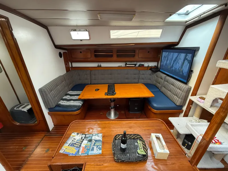 Interior of 1986 Beneteau Idylle 15.50 yacht with cozy seating and wooden table.