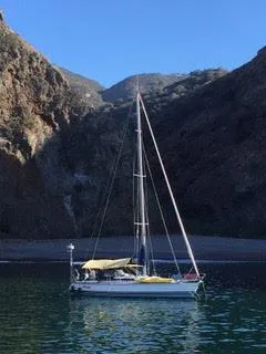 Sailboat X-Yachts X-382 (2002) anchored in a serene cove with rocky cliffs.