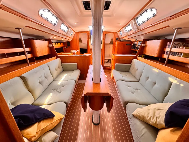 Luxurious interior of 2002 X-Yachts X-382 sailboat with plush seating and wooden finishes.