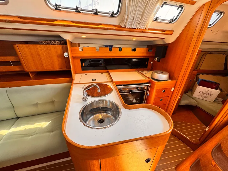 Interior of 2002 X-Yachts X-382 sailboat with wooden cabinetry and compact kitchen area.