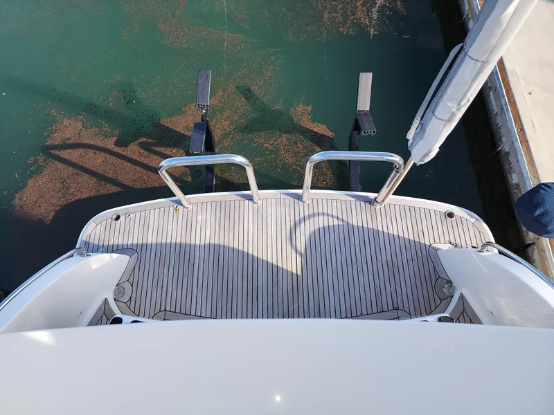 2007 Ocean Alexander Veloce yacht swim platform with stainless steel railings, docked in calm water.