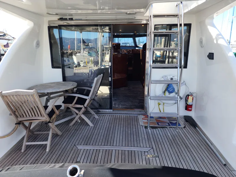 Outdoor deck of 2007 Ocean Alexander Veloce yacht with table, chairs, and ladder.