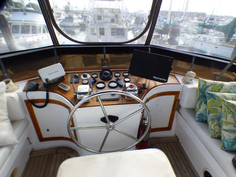 1984 Spindrift 39 ft. Aft Cabin helm with steering wheel, navigation instruments, and marina view.