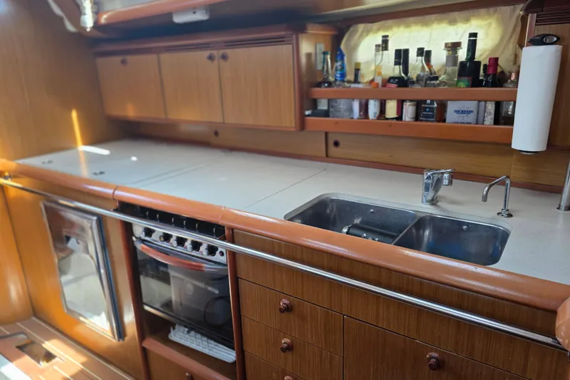 2007 Jeanneau 49 Performance yacht kitchen with wooden cabinets, dual sink, and stove.