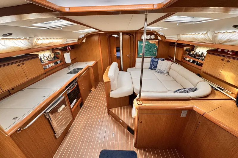 Luxurious interior of 2007 Jeanneau Sun Odyssey 49 Performance yacht with wood finish and white seating.