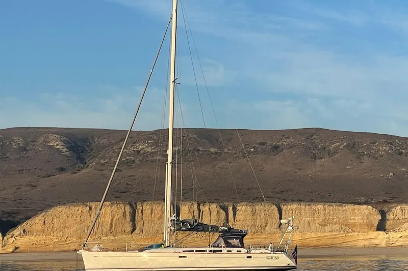 2007 Jeanneau Sun Odyssey 49 Performance sailboat against rocky coastal backdrop.