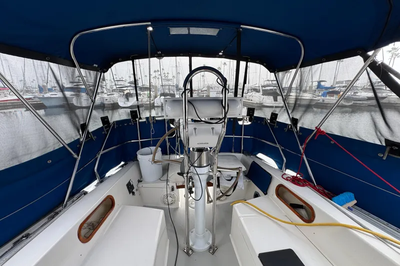 Interior view of 1991 Catalina 36MKI sailboat cockpit with blue canopy and marina background.