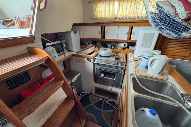 Compact kitchen in a 1991 Catalina 36MKI sailboat with wooden cabinetry and appliances.