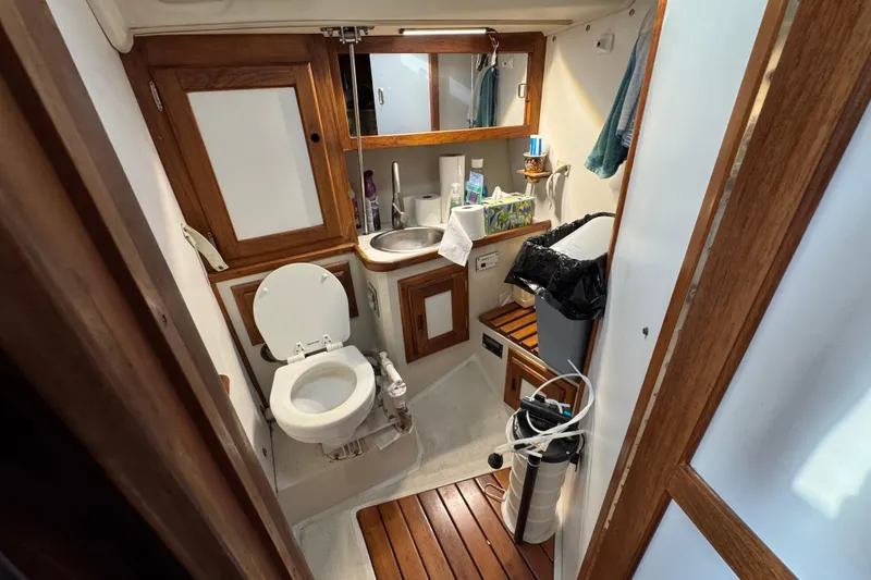 1991 Catalina 36MKI yacht bathroom with wooden accents, toilet, sink, and storage cabinets.