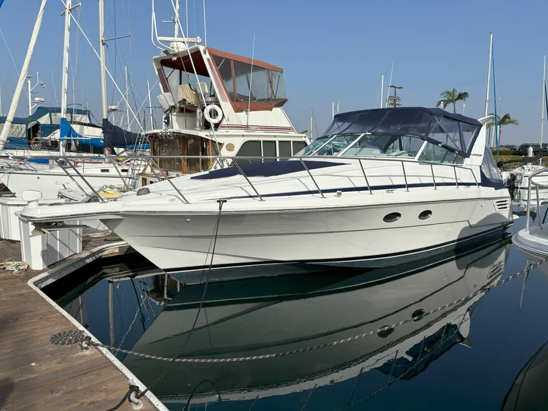 1998 Trojan 400 yacht docked at marina, clear sky, calm water reflection.