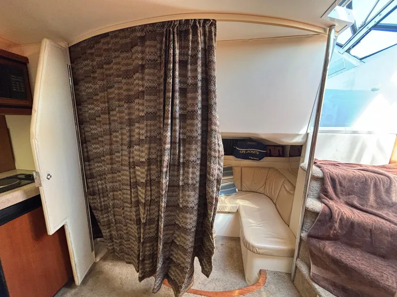 Interior of a 1998 Trojan 400 boat with a cozy seating area and privacy curtain.