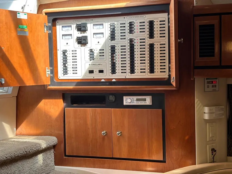 Electrical panel inside a 1998 Trojan 400 boat, featuring wooden cabinetry and control switches.