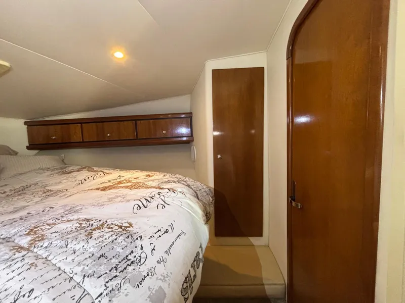 Cozy cabin interior of a 1998 Trojan 400 boat with wooden accents and a comfortable bed.