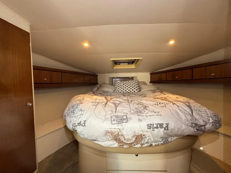 1998 Trojan 400 boat cabin with cozy bed, wooden cabinets, and soft lighting.