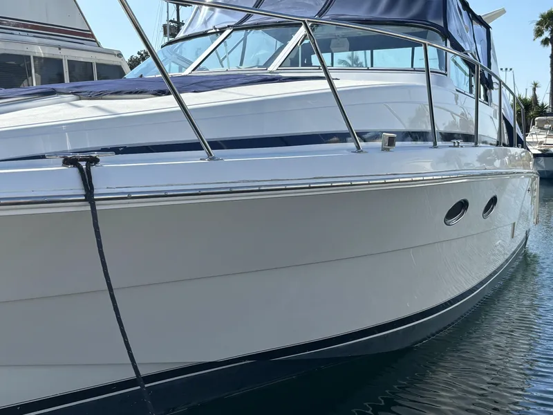 1998 Trojan 400 boat docked, featuring sleek design and blue canopy.
