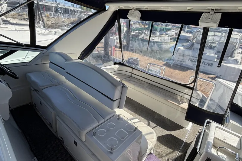 Interior of a 1998 Trojan 400 yacht with white seating and marina view.