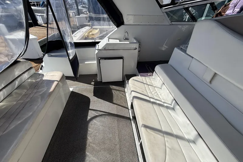 Interior of a 1998 Trojan 400 yacht with white seating and compact kitchenette.