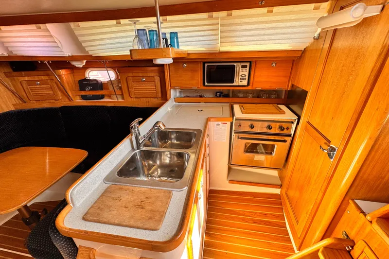 Interior of 2006 Catalina 34 MkII sailboat kitchen with wood cabinetry and modern appliances.