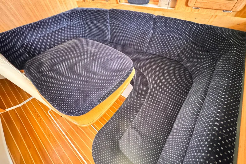 Interior of a 2006 Catalina 34 MkII sailboat with plush navy seating and wooden flooring.