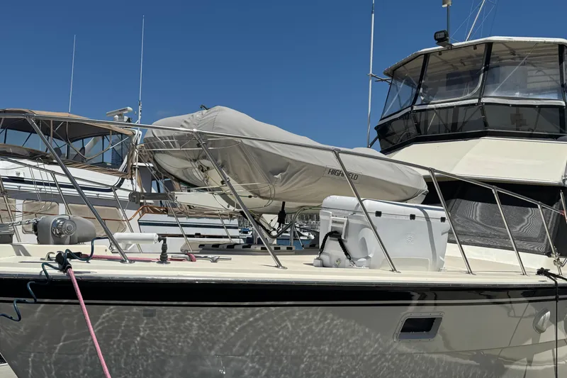 1985 Hatteras 45 Convertible yacht docked, featuring covered equipment and clear blue sky.