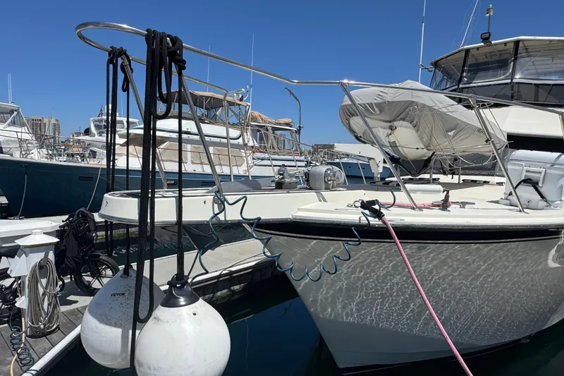 1985 Hatteras 45 Convertible yacht docked at marina under clear blue sky.
