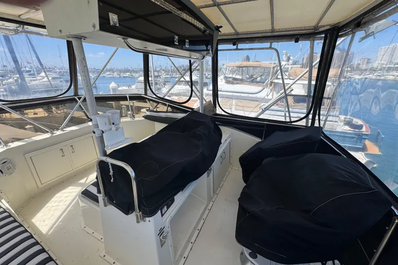 Interior view of 1985 Hatteras 45 Convertible yacht cockpit with covered seats and marina backdrop.