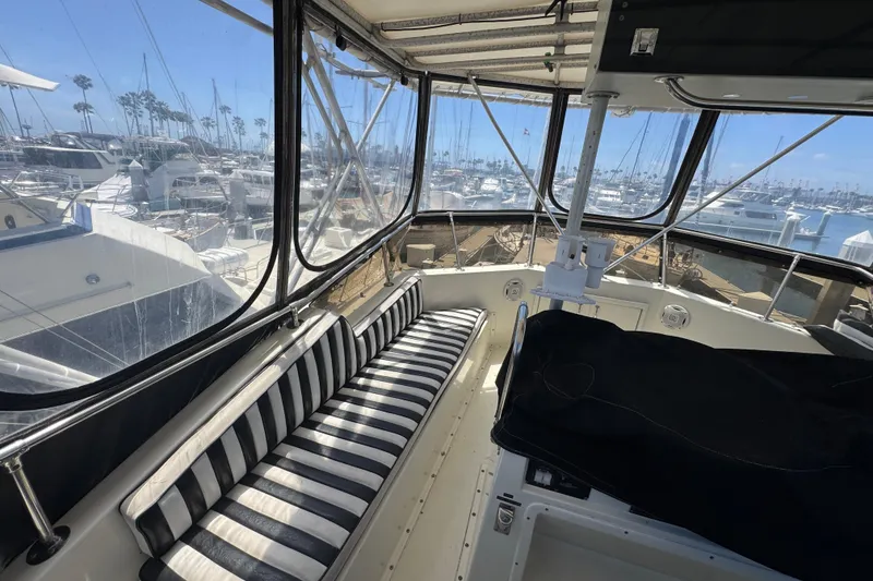 Interior view of 1985 Hatteras 45 Convertible yacht with striped seating and marina backdrop.