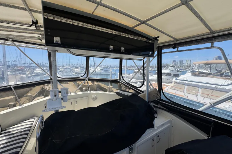Interior view of 1985 Hatteras 45 Convertible yacht at marina, showcasing helm and seating area.